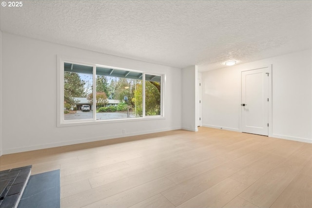 unfurnished room featuring a textured ceiling, light wood-style flooring, and baseboards