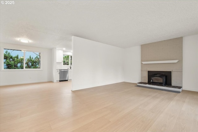 unfurnished living room featuring a textured ceiling, baseboards, and light wood-style floors