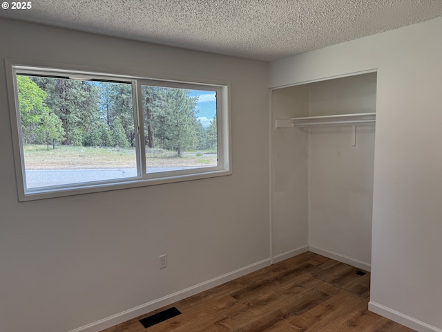 807 Glover St, Goldendale, WA 98620 - unfurnished bedroom featuring multiple windows, wood finished floors, a closet, a textured ceiling, and baseboards