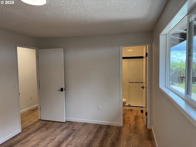807 Glover St, Goldendale, WA 98620 - unfurnished bedroom with wood finished floors, a textured ceiling, baseboards, and connected bathroom