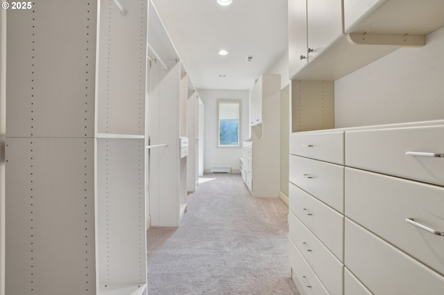 walk in closet with a baseboard heating unit and light carpet