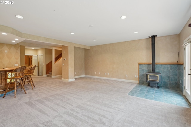 unfurnished living room featuring stairs, recessed lighting, light colored carpet, and a wood stove