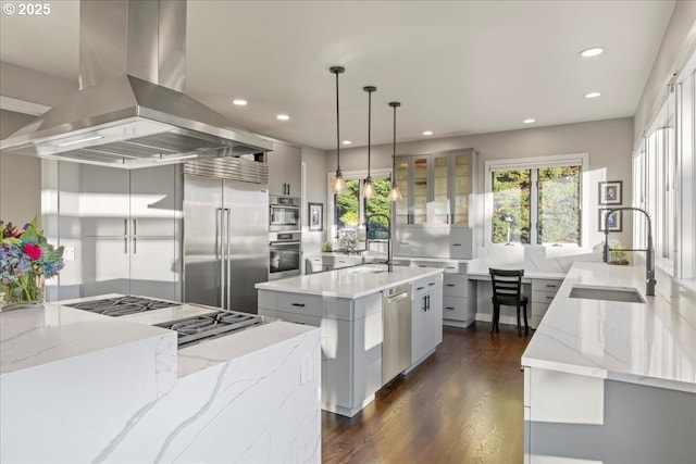 kitchen with pendant lighting, sink, island exhaust hood, stainless steel appliances, and a spacious island