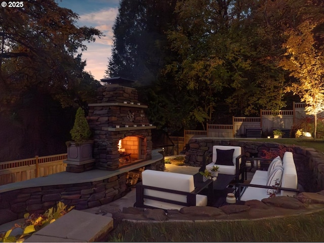 patio terrace at dusk featuring an outdoor stone fireplace