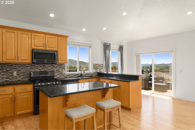 15708 SE Bybee Dr, Portland, OR 97236 - kitchen with gas range, a kitchen island, decorative backsplash, light wood-type flooring, and recessed lighting