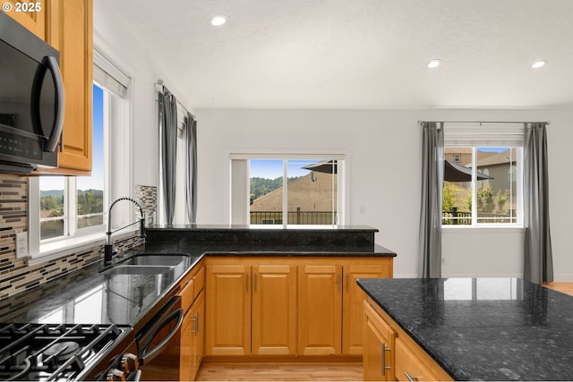 15708 SE Bybee Dr, Portland, OR 97236 - kitchen with black appliances, decorative backsplash, recessed lighting, dark stone counters, and a peninsula