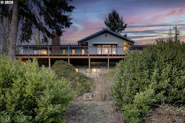 back of house at dusk with a chimney