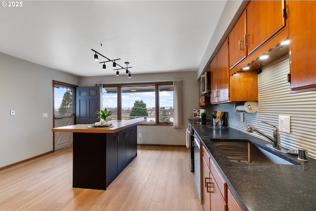 kitchen with brown cabinetry, a sink, light wood finished floors, and decorative backsplash