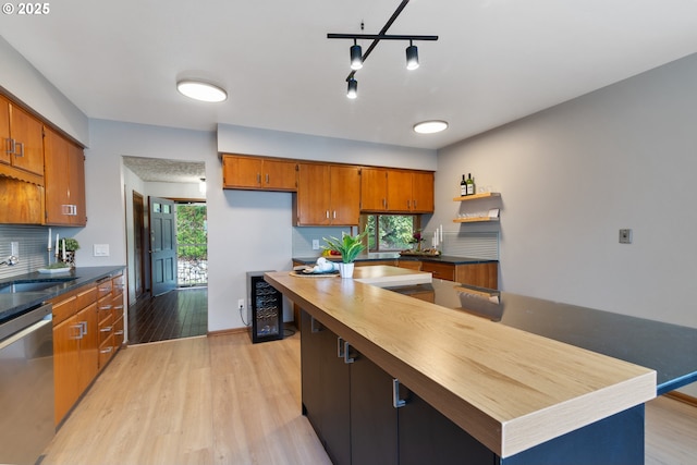 kitchen featuring brown cabinets, light wood-style floors, a sink, wood counters, and dishwasher