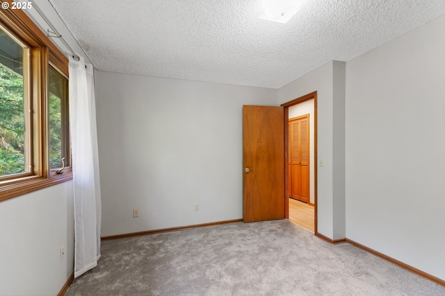 unfurnished room with carpet floors, a textured ceiling, and baseboards