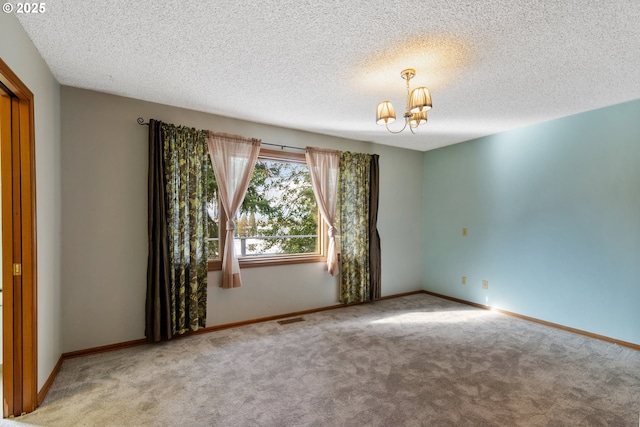 empty room with baseboards, visible vents, a textured ceiling, carpet floors, and a notable chandelier