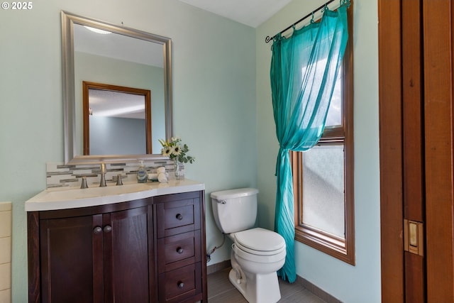 bathroom with toilet, tasteful backsplash, baseboards, and vanity