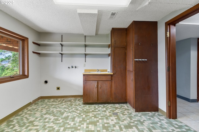 clothes washing area featuring washer hookup, visible vents, hookup for an electric dryer, a sink, and baseboards