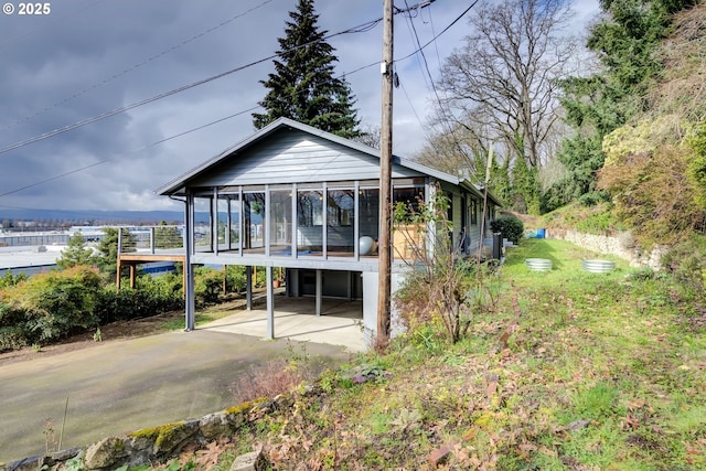 rear view of house featuring a carport, a sunroom, and driveway