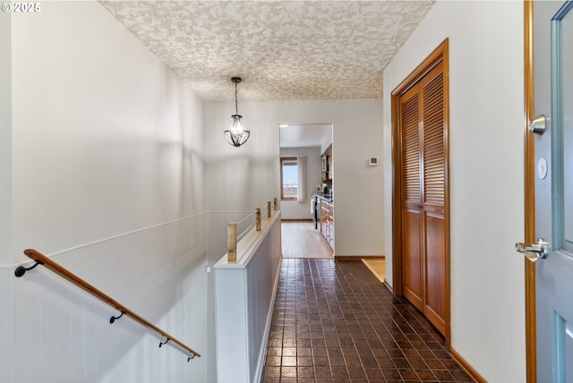 hallway featuring a textured ceiling and an upstairs landing