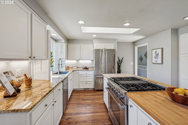 209 Mcnary Estates Dr N, Keizer, OR 97303 - kitchen with appliances with stainless steel finishes, a skylight, white cabinetry, recessed lighting, and dark wood-style flooring