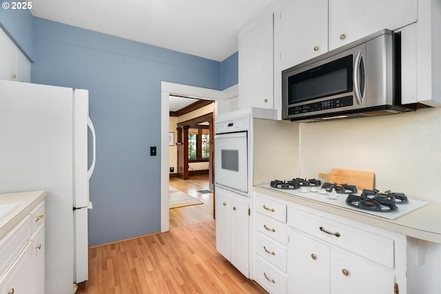 2522 NE 50th Ave, Portland, OR 97213 - kitchen featuring white appliances, light countertops, light wood-style floors, and white cabinets