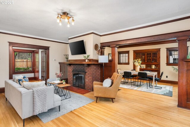 2522 NE 50th Ave, Portland, OR 97213 - living room featuring wood finished floors, a brick fireplace, crown molding, ornate columns, and baseboards