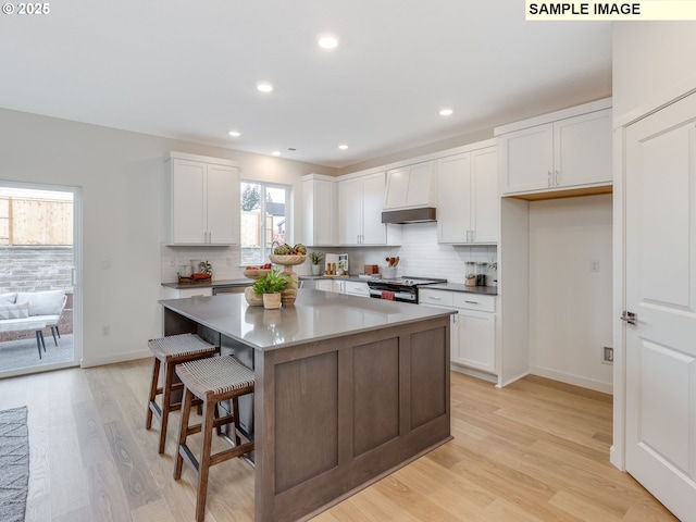 239 NW 29th Way, Battle Ground, WA 98604 - kitchen with white cabinets, stainless steel range with electric stovetop, a center island, decorative backsplash, and light wood-type flooring