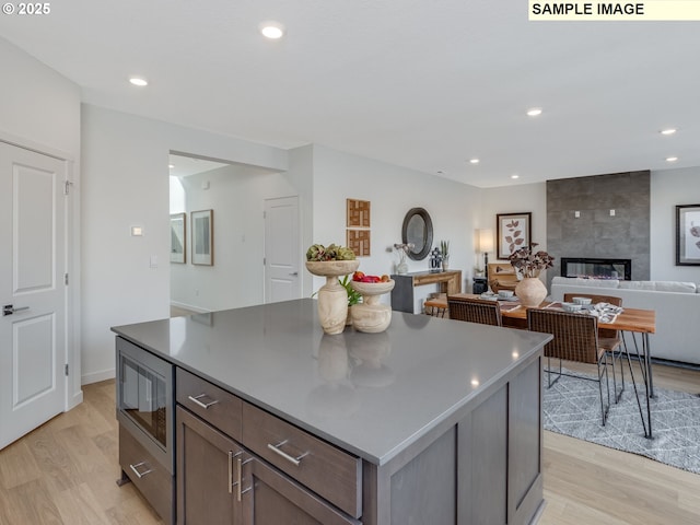 239 NW 29th Way, Battle Ground, WA 98604 - kitchen featuring a kitchen island, a fireplace, recessed lighting, stainless steel microwave, and light wood finished floors