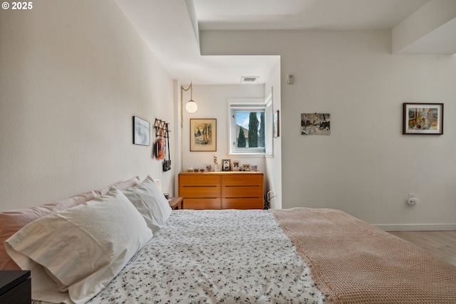 bedroom with baseboards, wood finished floors, and visible vents
