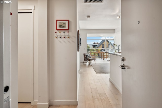 hallway with light wood-type flooring and baseboards