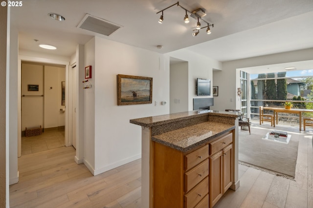 kitchen featuring dark stone counters, baseboards, light wood-style floors, and a kitchen island