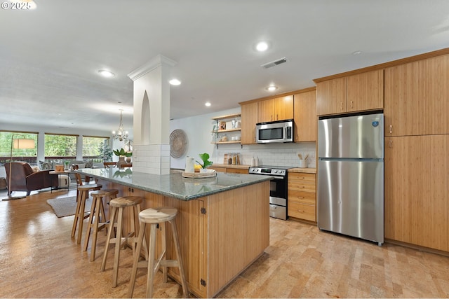 6708 N Richmond Ave, Portland, OR 97203 - kitchen with appliances with stainless steel finishes, a breakfast bar area, open floor plan, decorative backsplash, and visible vents