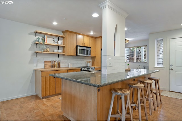 6708 N Richmond Ave, Portland, OR 97203 - kitchen with stainless steel appliances, recessed lighting, a kitchen breakfast bar, and tasteful backsplash