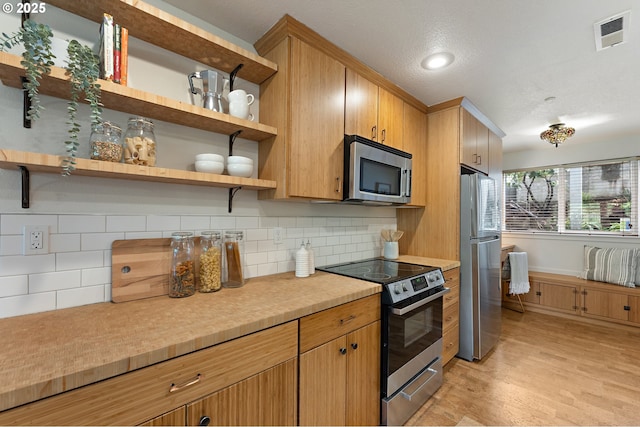 6708 N Richmond Ave, Portland, OR 97203 - kitchen featuring visible vents, decorative backsplash, light countertops, light wood finished floors, and stainless steel appliances
