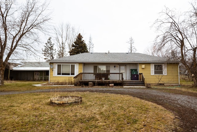 single story home with a fire pit, a front yard, and a wooden deck