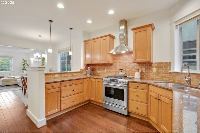 kitchen featuring dark wood-type flooring, wall chimney exhaust hood, sink, stainless steel range with gas stovetop, and pendant lighting