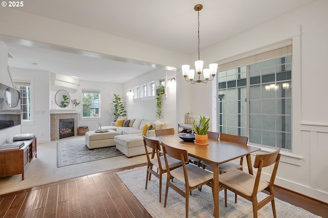 dining room with a tiled fireplace, a notable chandelier, and light hardwood / wood-style floors