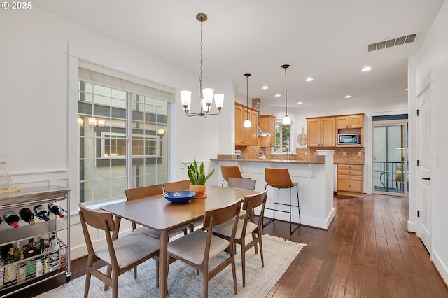 dining space with dark hardwood / wood-style floors and a chandelier