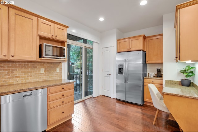 kitchen featuring dark wood-type flooring, light brown cabinetry, stainless steel appliances, light stone countertops, and decorative backsplash