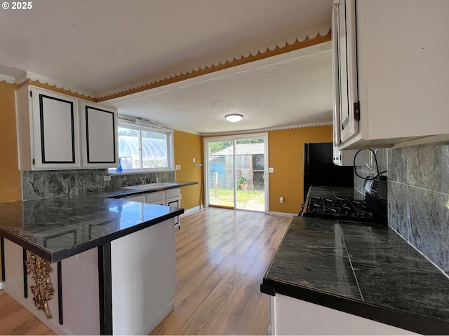 1042 Fir Ave, Reedsport, OR 97467 - kitchen featuring black appliances, light wood-style flooring, backsplash, white cabinets, and a peninsula