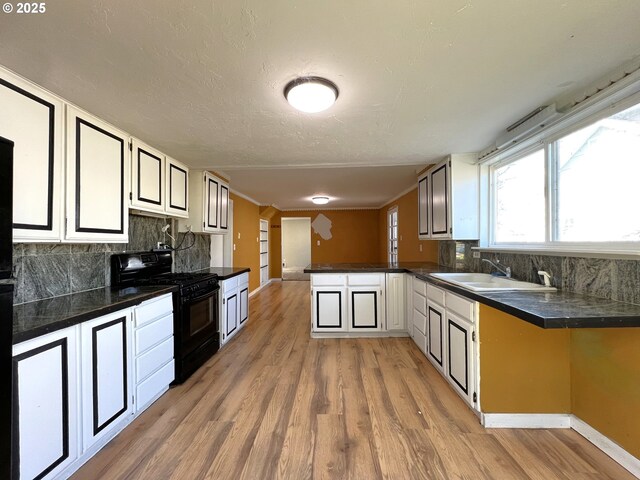 1042 Fir Ave, Reedsport, OR 97467 - kitchen with black gas range oven, backsplash, dark countertops, light wood-style floors, and a peninsula