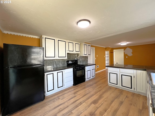 1042 Fir Ave, Reedsport, OR 97467 - kitchen featuring black appliances, dark countertops, light wood-style flooring, backsplash, and white cabinetry