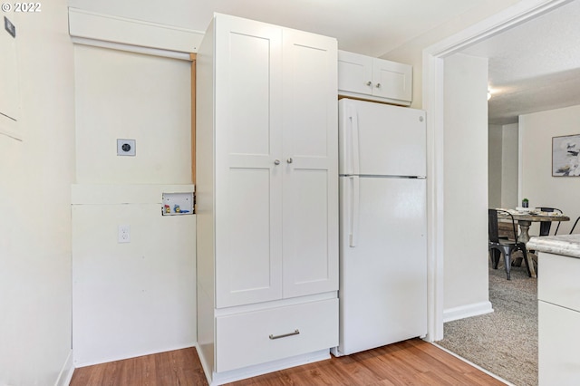 kitchen featuring light countertops, freestanding refrigerator, white cabinets, and light wood-style flooring