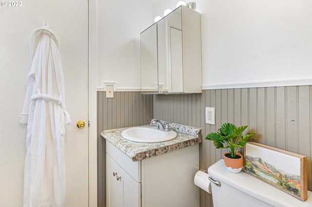 bathroom with wainscoting, vanity, and toilet