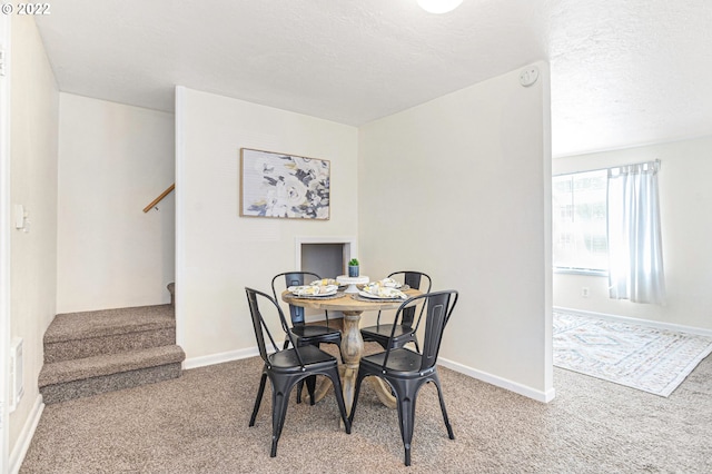 carpeted dining space featuring baseboards, stairway, and a textured ceiling