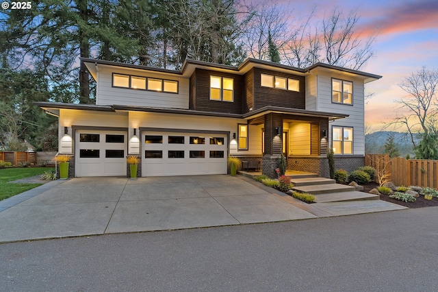 view of front facade with stone siding, fence, driveway, and an attached garage