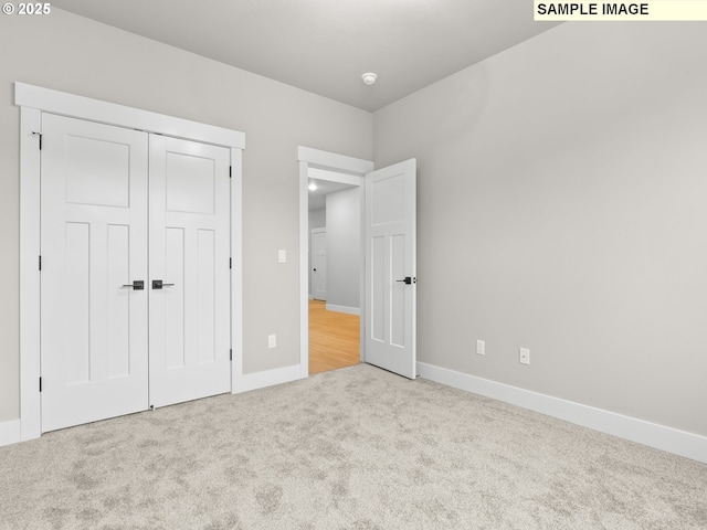 unfurnished bedroom featuring a closet, light carpet, and baseboards