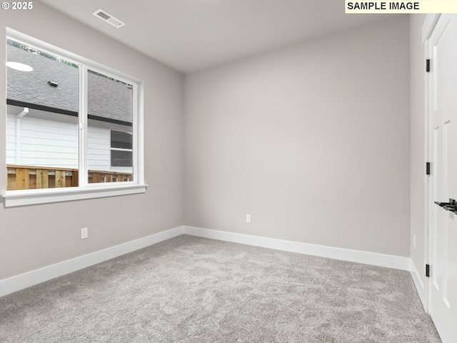 carpeted spare room featuring a wealth of natural light, visible vents, and baseboards