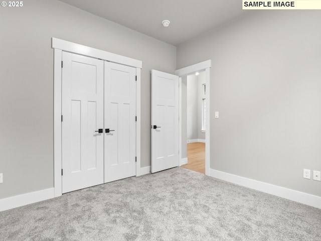 unfurnished bedroom with baseboards, a closet, and light colored carpet