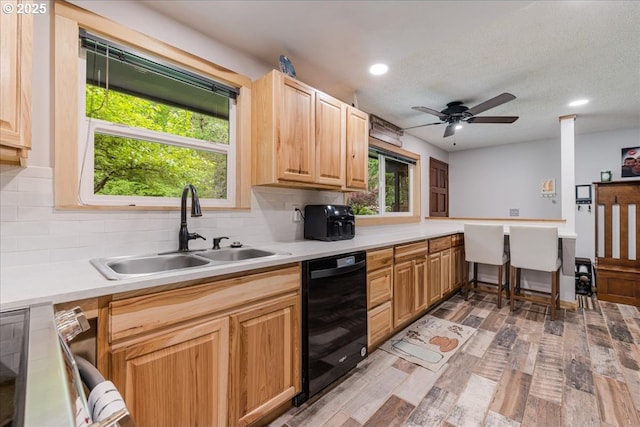 kitchen featuring dishwasher, a sink, backsplash, recessed lighting, and light countertops