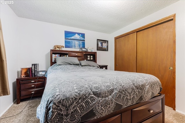 bedroom with light carpet, a closet, a textured ceiling, and baseboards