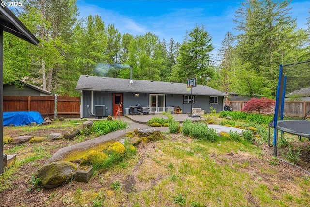 back of property with a trampoline, a patio area, a fenced backyard, and cooling unit