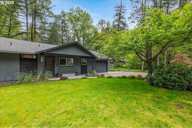 back of property featuring an attached garage, driveway, a yard, and roof with shingles