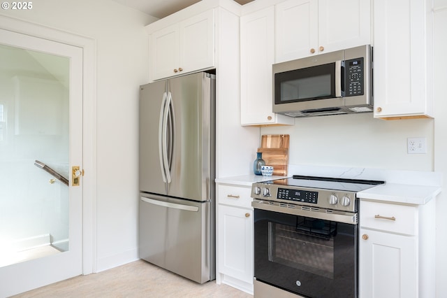 7327 N Washburne Ave, Portland, OR 97217 - kitchen with appliances with stainless steel finishes, light countertops, white cabinetry, and light wood-style flooring